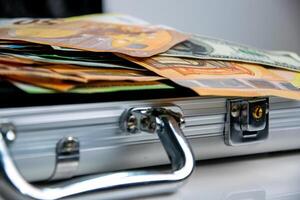 A close up image of a metal case partially open, revealing a stack of euro bills photo