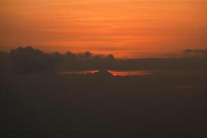 Sunset behind clouds and silhouetted hills photo
