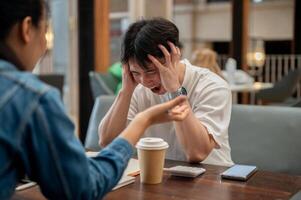 A stressed Asian man is expressing frustration and a headache, screaming while discussing work. photo