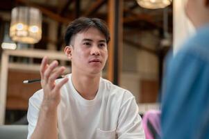 A handsome Asian man is having an informal meeting with his colleagues at a cafe, sharing his ideas. photo