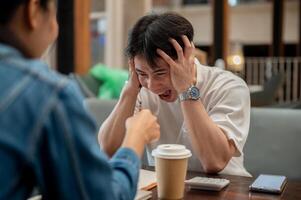 A stressed Asian man is expressing frustration and a headache, screaming while discussing work. photo