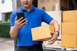 An Asian delivery guy is checking a customer's address on his smartphone before making the delivery. photo