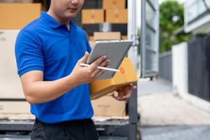 A delivery guy checking the address on his tablet while carrying a package for delivery. photo