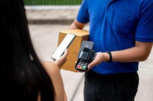 A customer tapping her smartphone on a card reader before receiving a package from a delivery man. photo