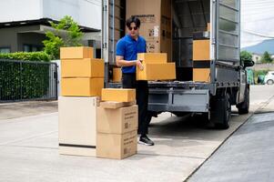 An Asian delivery man or mover is unloading cardboard boxes from his truck. photo