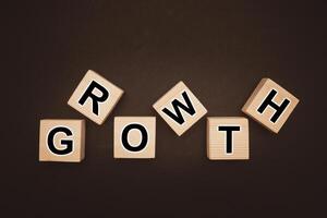 Overhead view of wooden cubes with words GROWTH over a black background photo