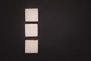 Overhead view of blank three wooden cubes on a black background with space for text photo