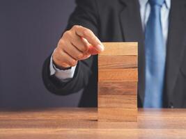 Hand of a businessman arranging empty wooden block on wooden table photo