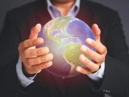 Save the earth and environment concept. Businessman holding the world while standing over a gray background photo