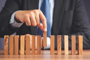 Business and risk management. A businessman pick up a wooden block while sitting in the office photo