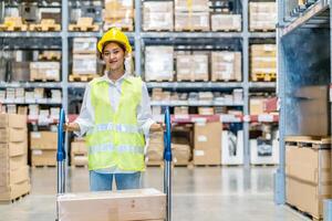 Portrait of employee female warehouse professional worker in uniform working in inventory with stacked up shelves in logistics center factory, Warehouse operation carry carton box keep in the shelf photo
