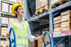 Portrait of employee female warehouse professional worker in uniform working in inventory with stacked up shelves in logistics center factory, Warehouse operation carry carton box keep in the shelf photo