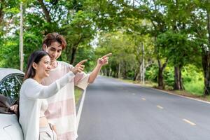Young asian couple get out of the car and walk to enjoying the view, standing near the car, Man and woman looking at sunset and beautiful nature, Boy and girl standing by the machine photo