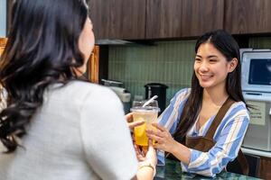 Smiling young asian waitress in a cafe with customer for service, payment or order on counter at coffee shop. Serving, employee in small business restaurant helping a girl client at checkout or work photo