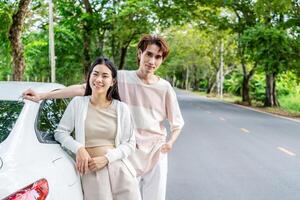 Young asian couple get out of the car and walk to enjoying the view, standing near the car, Man and woman looking at sunset and beautiful nature, Boy and girl standing by the machine photo