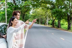 Young asian couple get out of the car and walk to enjoying the view, standing near the car, Man and woman looking at sunset and beautiful nature, Boy and girl standing by the machine photo