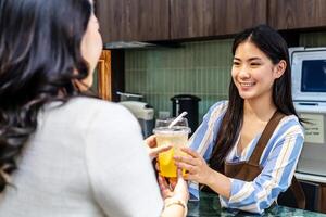 Smiling young asian waitress in a cafe with customer for service, payment or order on counter at coffee shop. Serving, employee in small business restaurant helping a girl client at checkout or work photo