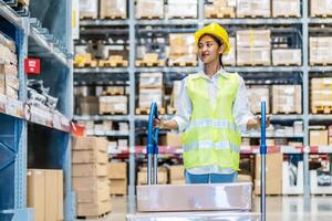 Portrait of employee female warehouse professional worker in uniform working in inventory with stacked up shelves in logistics center factory, Warehouse operation carry carton box keep in the shelf photo