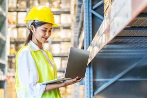 Portrait of asian woman warehouse worker in uniform checks stock and inventory with digital laptop computer, working in delivery, distribution center, logistic and business export photo