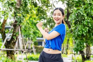 Strong athletic asian woman stretching warming up before running. Fit sport girl stretching her body warm up before workout outdoor. The girl in sportswear exercises outside for health and wellbeing photo