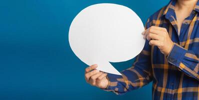 Midsection of a young man holding a blank paper while standing with blue background in the studio. A speech bubble concept photo