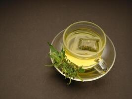 Cannabis tea in a teacup and marijuana buds flowers on a gray background photo