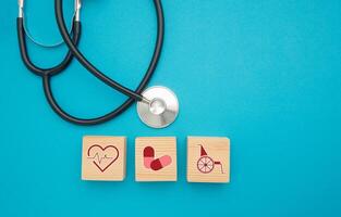 Top view of a stethoscope and wooden cubes with health icons isolated on a light blue background photo