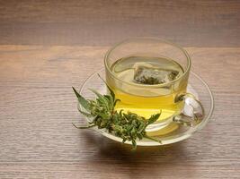 Cannabis tea in a teacup and marijuana buds flower isolated on a wooden table photo