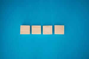 Top view of blank four wooden cubes on a blue background with space for text photo