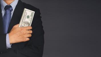 Businessman in suit holding US banknotes while standing in the studio. Business and finance concept photo