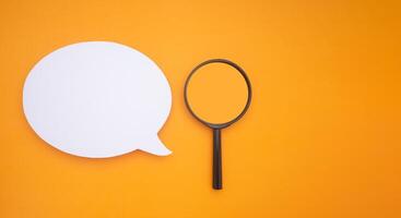 Top view of a blank white speech bubble and a magnifying glass isolated on a yellow background. Space for text photo