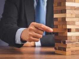 Risk of management and strategy plans for business growth and success concept. Close-up hand of the businessman in a suit playing a wooden block game while sitting at the work table photo