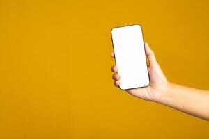 Technology and communication concept. Hand holding a mobile phone with copy space for text isolated yellow background photo