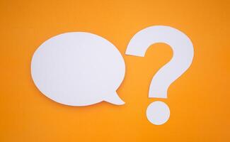 Speech bubble concept. An empty speech balloons and question mark symbol isolated on yellow background with copy space for text. Close-up photo. Top view photo