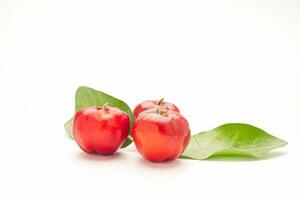 Ripe red acerola cherry fruit and green leaves isolated on white background. High vitamin C and antioxidant fruits. Top view. Space for text. Concept of healthy fruits photo