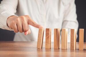 Close-up of hand push a wooden block on a line of domino. Risk and strategy in business concept photo