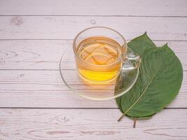 Top view of Mitragyna Speciosa or Kratom leaves with a teacup on a wooden table with copy space for text. Close-up photo. Medical and herbal concept photo