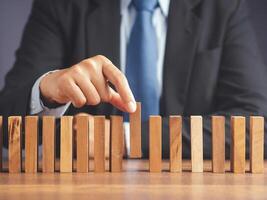 Business and risk management concept. A businessman in a suit picks up a wooden block while sitting in the office. Conceptual of planning, strategy. Close-up photo. photo