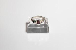 plata anillo con verde y rojo piedras preciosas en blanco fondo, elegante joyería para especial ocasiones. foto