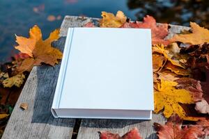 a white book for mockup on wooden table, top view next to yellow autumn maple leaf. Mockup, empty space, place for text. photo