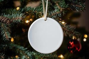 a white round ceramic sublimation decoration on Christmas tree. photo