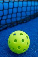 Selective focus. A pickleball ball near the net in a blue court. Racket sports concept. photo