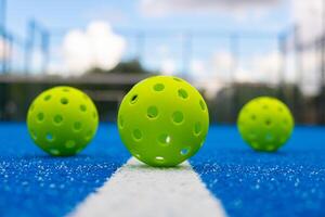 Selective focus, Three pickleball balls in a blue court photo