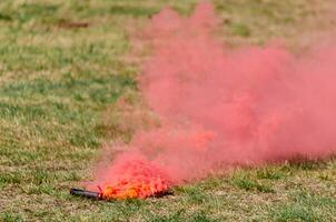 red smoke flare lying on a grassy field photo