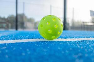 green pickleball ball isolated on the line of a court with the background out of focus. photo