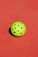 Pickleball ball isolated on red background, racket sport concept photo
