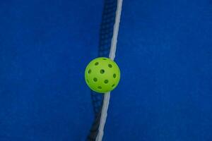 zenithal view of a pickleball ball on the net of a pickleball court, racket sports concept photo