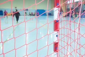 selective focus, netting of an indoor soccer goal with the players of the match out of focus in the background during a competition photo