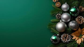 Christmas ornaments in silver and green with frosted pinecones and holiday greenery arranged on a rich green background. photo
