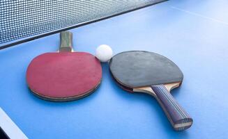two ping-pong rackets and a ball on a green table. Close-up, ping-pong net. photo